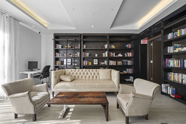 living area featuring built in shelves and a raised ceiling