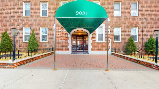 entrance to property with french doors, fence, and brick siding