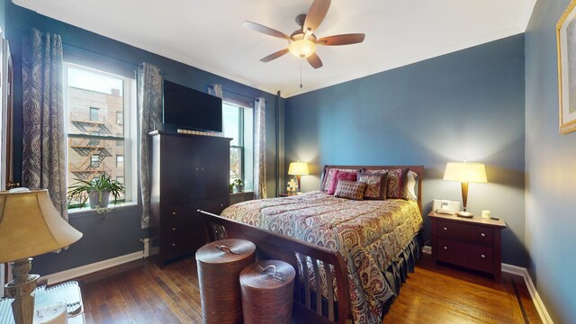 bedroom with a ceiling fan, baseboards, wood finished floors, and ornamental molding