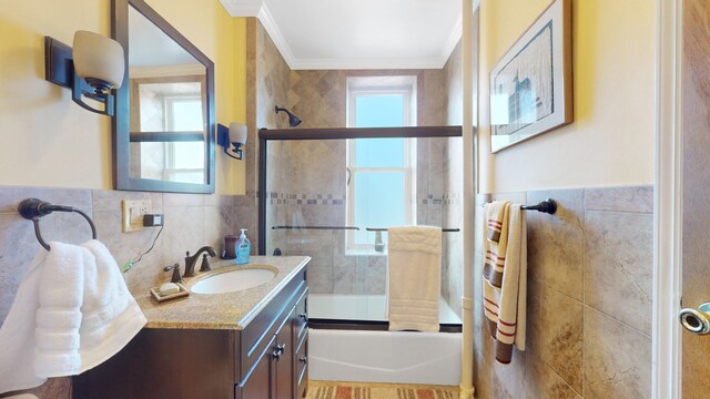 full bathroom with plenty of natural light, bath / shower combo with glass door, tile walls, and ornamental molding