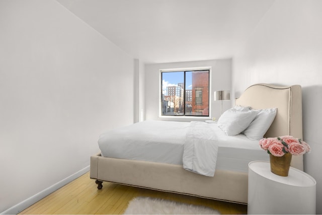 bedroom with wood-type flooring and baseboards