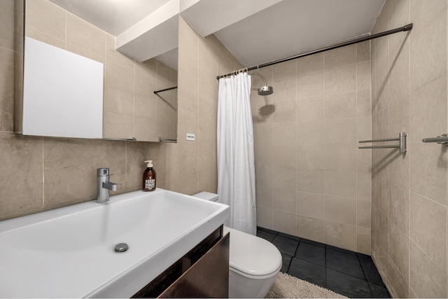 bathroom featuring tile walls, toilet, a tile shower, vanity, and tile patterned flooring