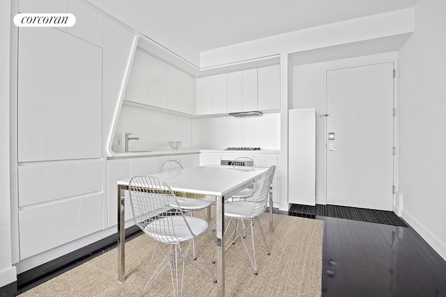 kitchen featuring a sink, white cabinetry, light countertops, dark wood-style floors, and modern cabinets