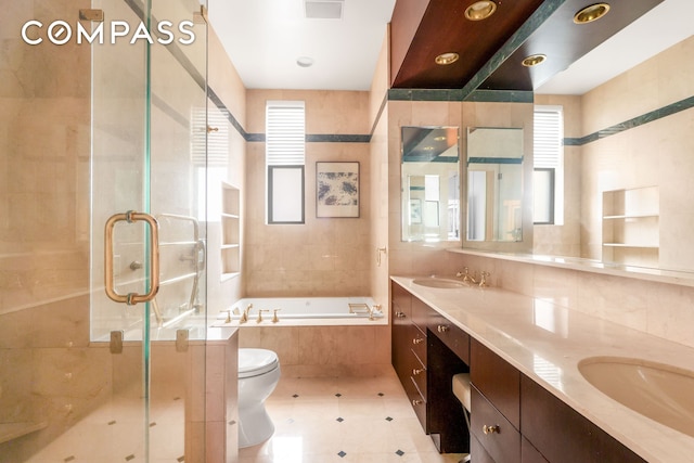 bathroom featuring toilet, a sink, a shower stall, a bath, and double vanity