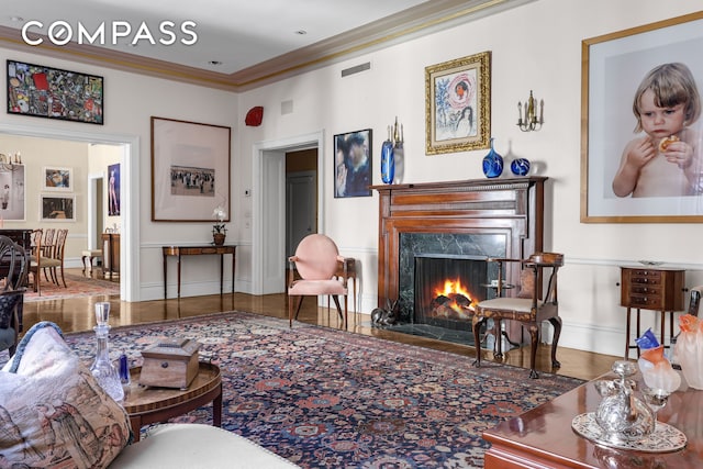 living room with ornamental molding, a fireplace, visible vents, and baseboards