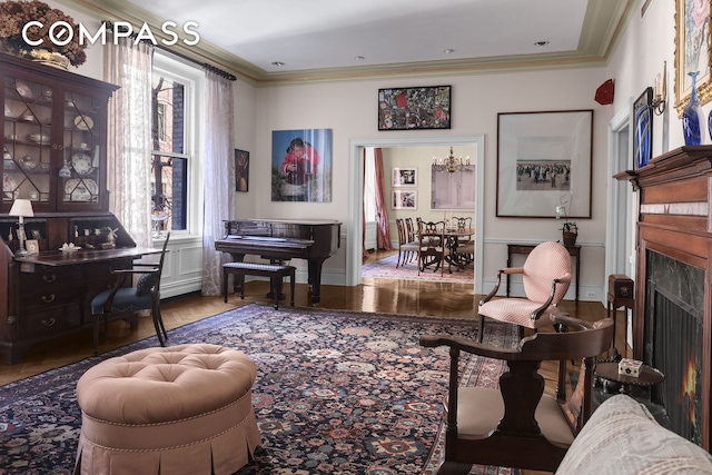 sitting room featuring a lit fireplace, baseboards, and crown molding