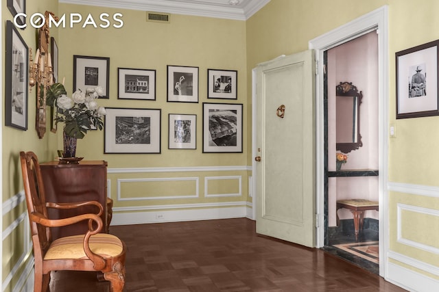 sitting room featuring a wainscoted wall, visible vents, a decorative wall, and ornamental molding