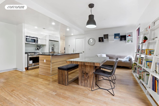 kitchen featuring a center island, decorative light fixtures, visible vents, appliances with stainless steel finishes, and white cabinets