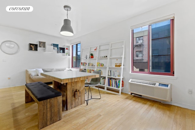 dining space with an AC wall unit, light wood finished floors, visible vents, and baseboards