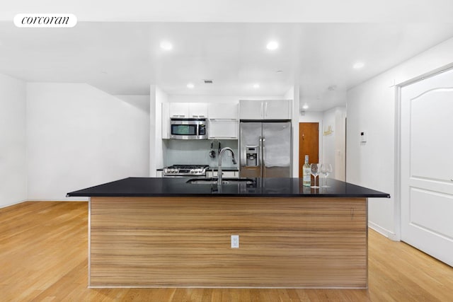 kitchen with visible vents, stainless steel appliances, light wood-style floors, white cabinetry, and a sink