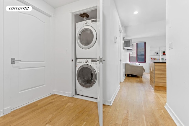 clothes washing area with visible vents, light wood-type flooring, stacked washing maching and dryer, and laundry area