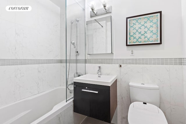 bathroom with tiled shower / bath, vanity, toilet, and tile walls