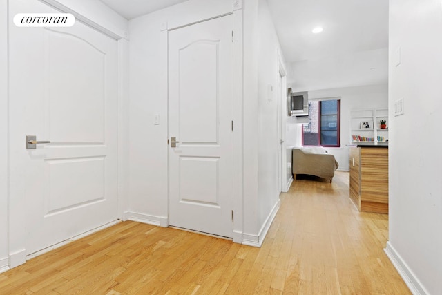 corridor with visible vents, light wood-style flooring, and baseboards