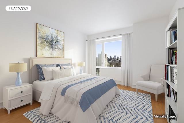 bedroom featuring light wood-type flooring, visible vents, and a city view