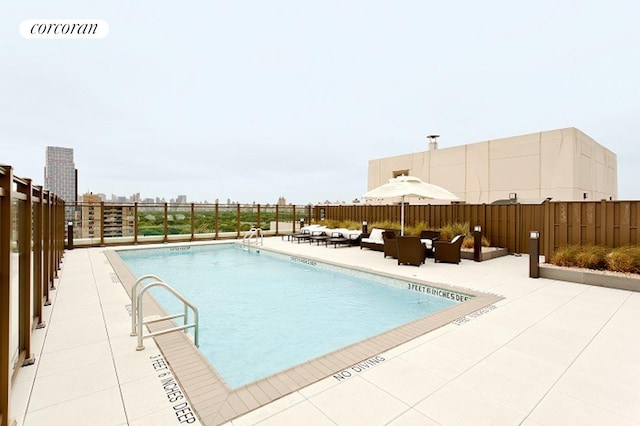 pool with a city view, a patio, and fence