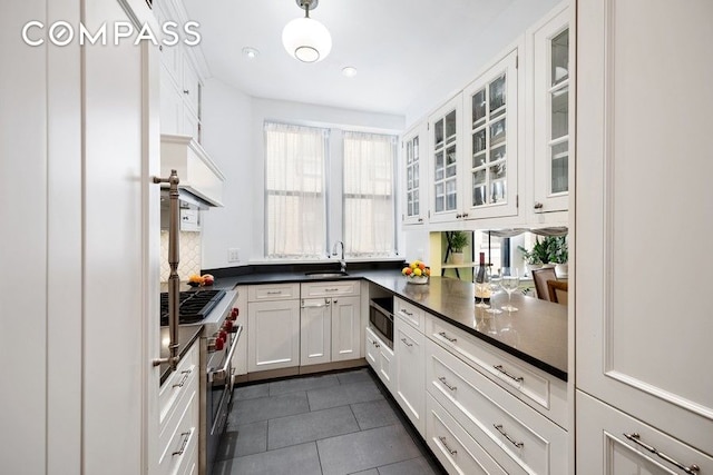 kitchen with appliances with stainless steel finishes, plenty of natural light, glass insert cabinets, and a sink