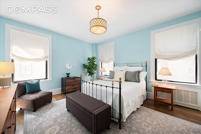 bedroom featuring radiator heating unit, baseboards, and wood finished floors