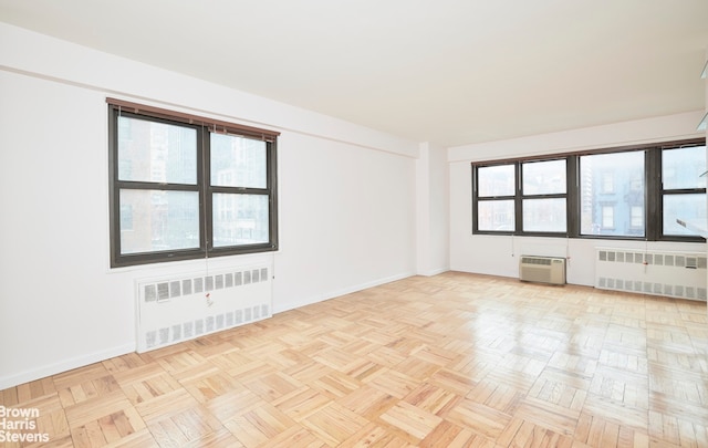 unfurnished room with radiator heating unit, baseboards, and a wall mounted air conditioner