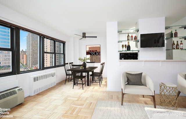 dining room with a view of city, ceiling fan, a wall unit AC, and radiator