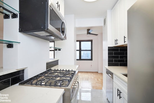 kitchen with appliances with stainless steel finishes, white cabinetry, and a ceiling fan