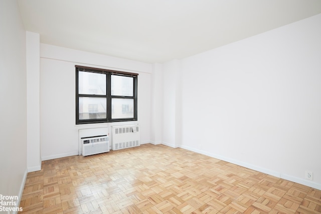 unfurnished room featuring baseboards, a wall mounted AC, and radiator