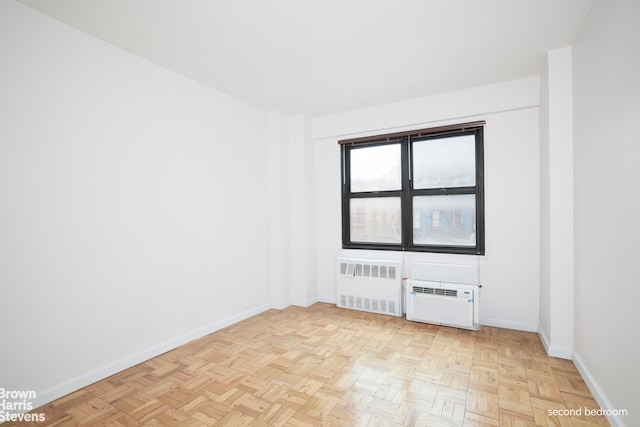 unfurnished room featuring radiator, a wall unit AC, and baseboards