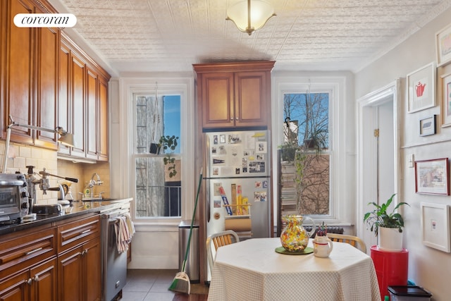 kitchen with plenty of natural light, tasteful backsplash, dishwasher, dark countertops, and freestanding refrigerator