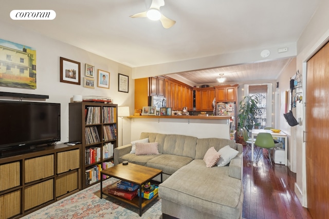 living area with a ceiling fan, visible vents, and wood finished floors