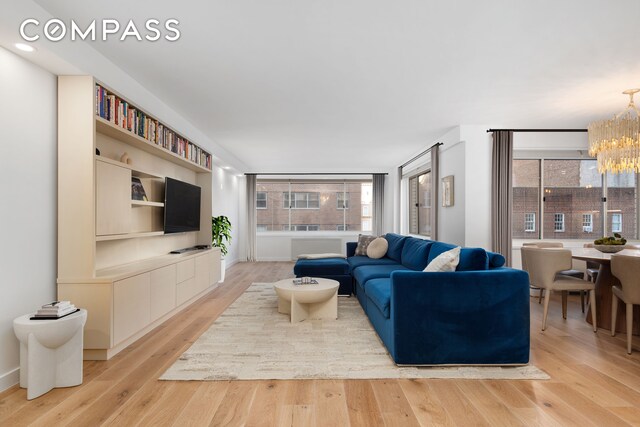 living area with an inviting chandelier, recessed lighting, light wood finished floors, and a healthy amount of sunlight