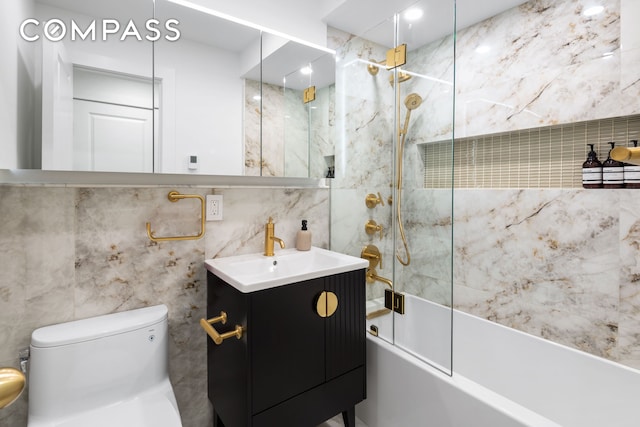 bathroom featuring vanity, bathing tub / shower combination, toilet, and tile walls