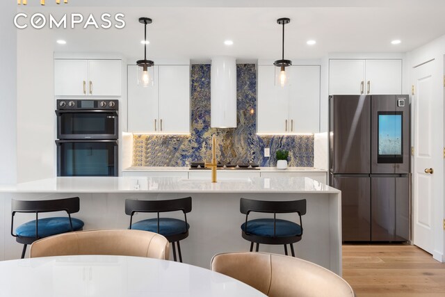 kitchen with decorative backsplash, hanging light fixtures, white cabinets, a breakfast bar, and stainless steel appliances