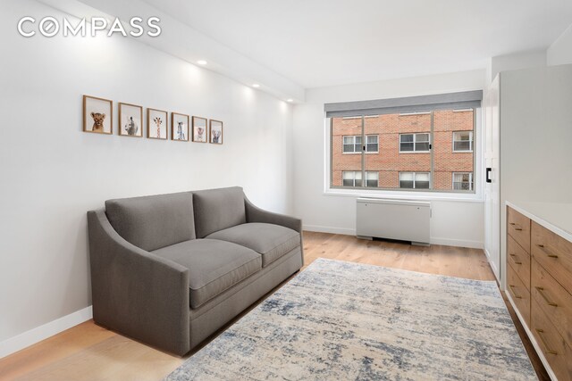 living area with radiator, baseboards, recessed lighting, and wood finished floors