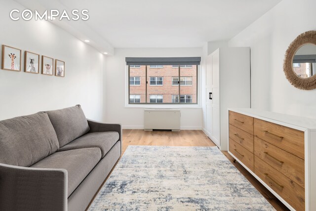 living room with wood finished floors, recessed lighting, baseboards, and radiator heating unit