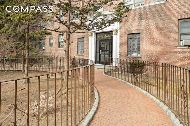 property entrance with fence and brick siding