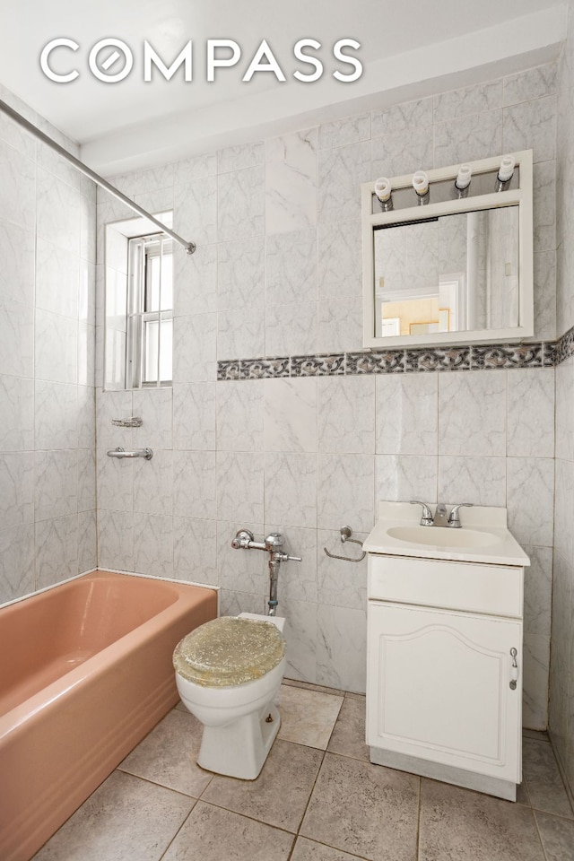 full bath with tile walls, tile patterned flooring, vanity, and bathing tub / shower combination