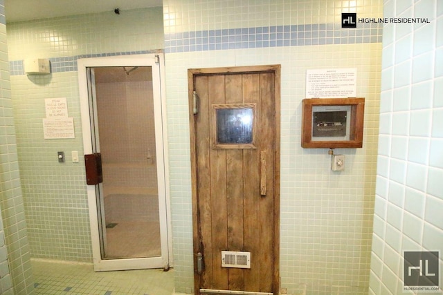 bathroom featuring a shower stall, visible vents, and tile walls