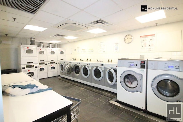 shared laundry area featuring stacked washer and dryer, visible vents, dark tile patterned floors, and washing machine and clothes dryer