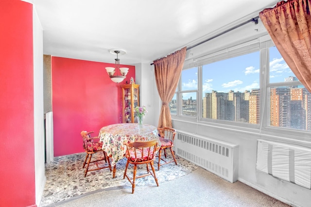 carpeted dining area with a notable chandelier, radiator heating unit, a view of city, and a wealth of natural light