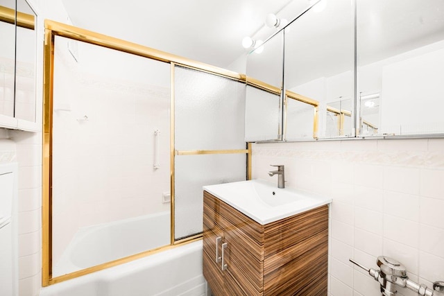 bathroom featuring bath / shower combo with glass door, tile walls, and vanity