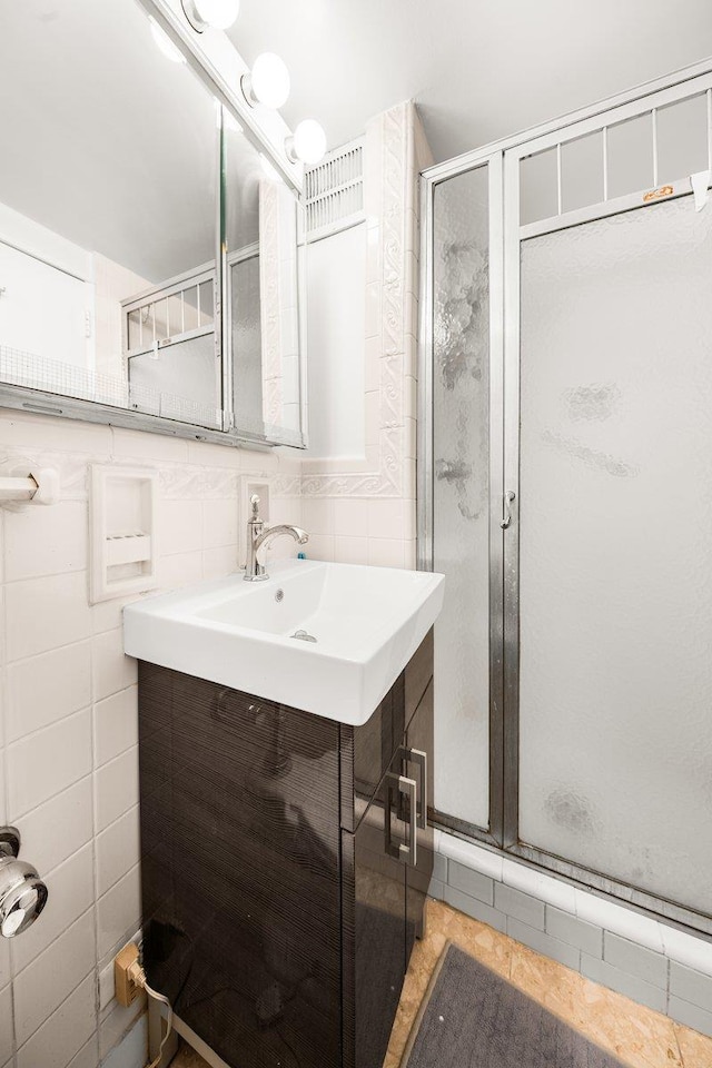 bathroom with a stall shower, vanity, and tile walls