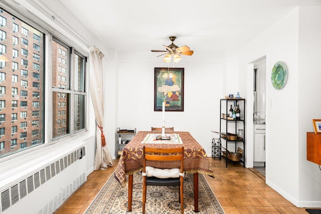 dining room with radiator heating unit, a ceiling fan, and baseboards