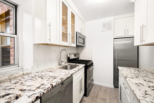 kitchen featuring stainless steel appliances, glass insert cabinets, and white cabinets