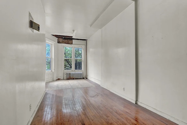 spare room featuring baseboards, radiator heating unit, and hardwood / wood-style flooring