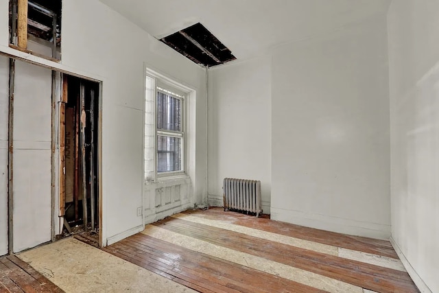 unfurnished room featuring radiator and hardwood / wood-style flooring