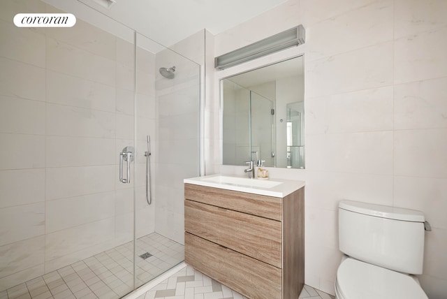 bathroom featuring a stall shower, vanity, toilet, and tile walls