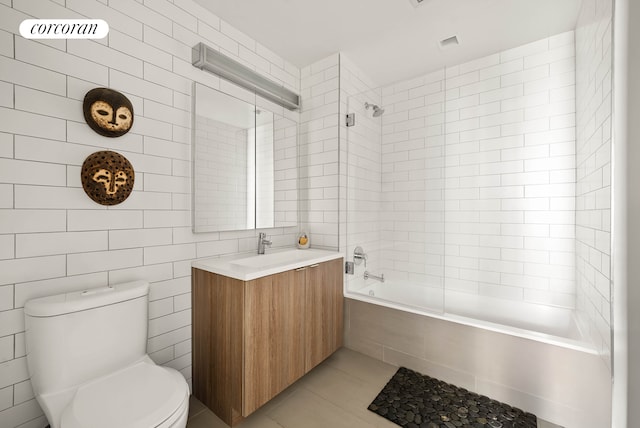 full bath with toilet, tile patterned floors, tiled shower / bath combo, vanity, and tile walls