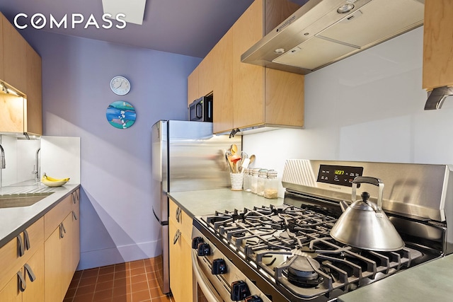 kitchen with light brown cabinets, a sink, light countertops, under cabinet range hood, and stainless steel gas range oven