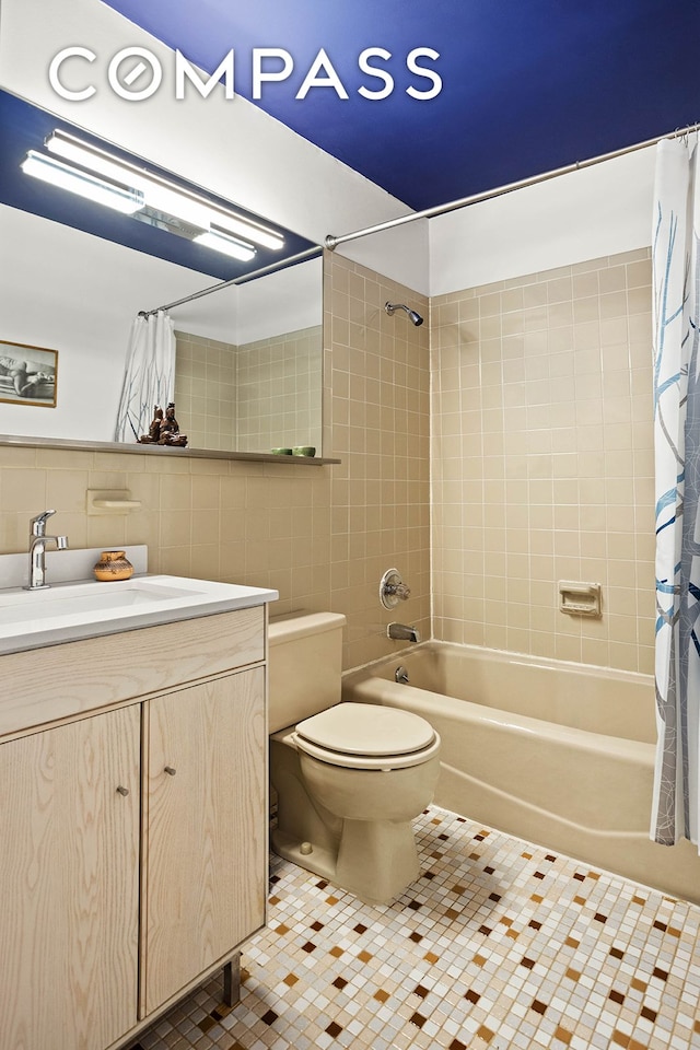 bathroom with tile patterned flooring, tile walls, toilet, shower / bath combo with shower curtain, and vanity