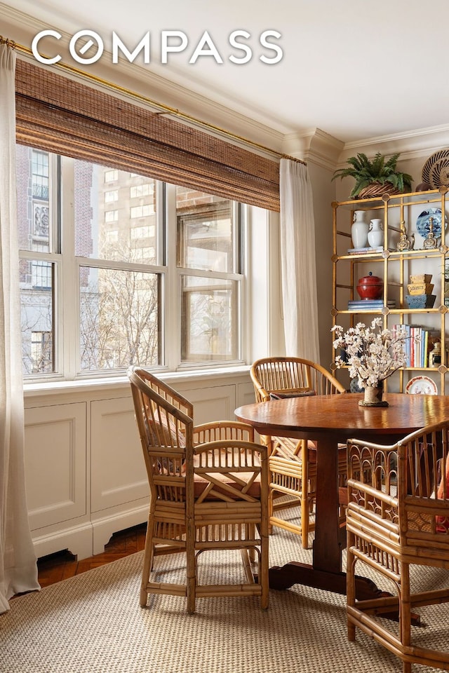 dining room with a healthy amount of sunlight, a decorative wall, and crown molding