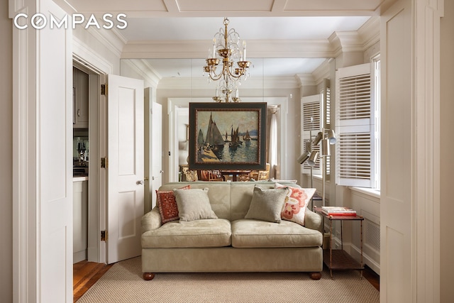 sitting room with a chandelier, light wood-type flooring, and crown molding